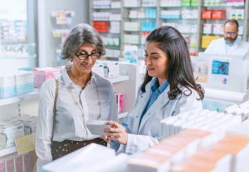 A pharmacist going over notes about prescription with a customer.