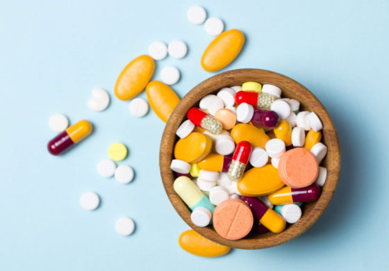 Pills and various medications in a bowl on a table top