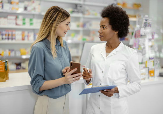 A pharmacist going over notes about prescription with a customer.